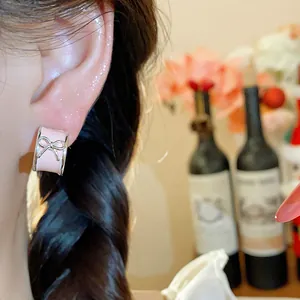 Close-up of pink enamel bow stud earring on model showing delicate fashion jewelry detail
