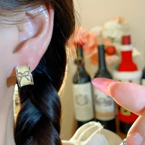 Close-up of a C-shaped earring with a cute bow motif and yellow enamel finish