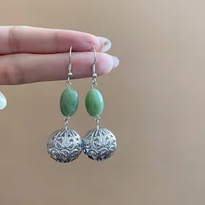 Detail of vintage neo-Chinese drop earrings with green beads and silver filigree balls