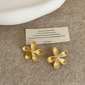 Macro view of elegant gold-tone flower stud earrings with textured petal details