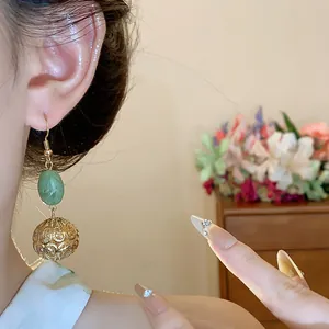 Close-up of elegant vintage resin and hollow gold ball drop earrings worn by a model