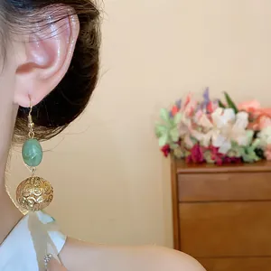 Close-up of vintage resin and gold hollow sphere drop earrings on ear