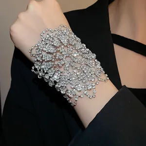 Close-up macro view of luxury wide rhinestone floral cuff bracelet worn with a black blazer