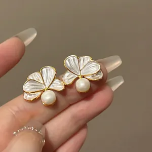 Detailed view of 18k gold-plated floral pearl stud earrings with pearlescent petals.