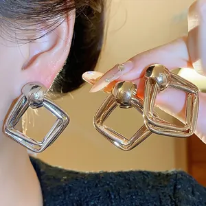 Orecchini in metallo geometrico minimalista in finitura oro e argento, indossati all'orecchio.
