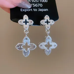 Close-up of silver-tone guilloche textured quatrefoil dangle earrings on display card