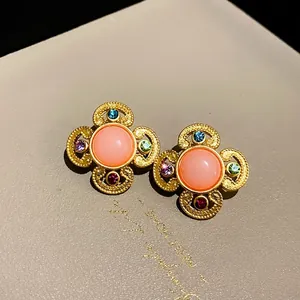 Vintage gold-tone earrings featuring a pink oval stone and multi-colored crystals.
