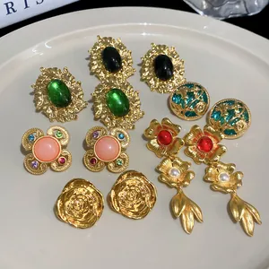 Detailed view of vintage gold earrings with floral patterns and colorful gemstones.