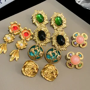 A detailed overhead view of diverse vintage-style gold earrings with colorful gemstones.