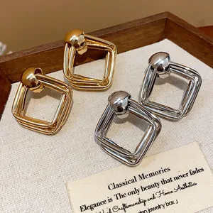 Primo piano di orecchini a perno quadrati geometrici in oro e argento