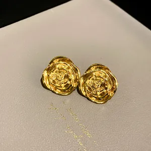 Close-up of vintage-style gold rose flower stud earrings with detailed petal texture