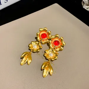 Detailed macro view of vintage gold flower and leaf earrings with red stones and pearls