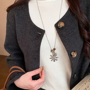 Elegant vintage flower necklace with tiger eye stone bead styled on a white turtleneck