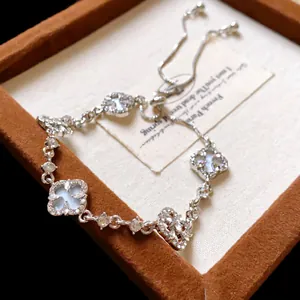Macro detail of silver four-leaf clover bracelet with pavé diamonds and shell inlay