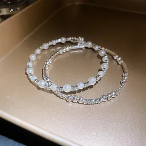 Primer plano de elegantes brazaletes abiertos con perlas luminosas y cristales brillantes