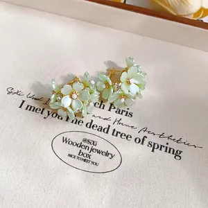 Primo piano di eleganti orecchini a lobo a fiore verde menta con perle e strass
