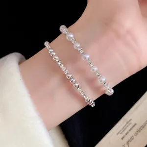 Primer plano de pulseras retro francesas con pedrería y perlas sobre una muñeca.
