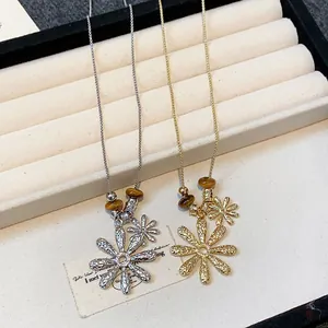 Detail of tiger eye bead and textured flower pendant necklaces in gold and silver