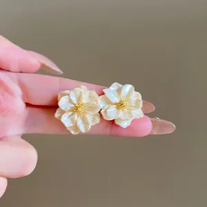 Primo piano di eleganti orecchini a lobo a fiore in madreperla crema con centro dorato