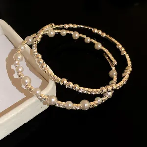 Primer plano de elegantes brazaletes abiertos plateados con perlas y diamantes