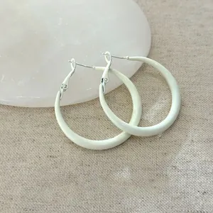 Orecchini a cerchio bianchi minimalisti con perni in argento per uno stile chic.