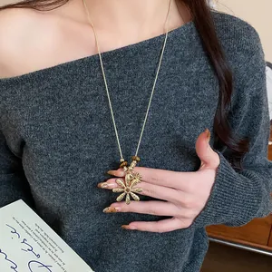 Detailed view of a golden flower pendant necklace with tiger eye beads on a model