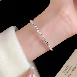 Elegante pulsera de cuentas plateadas con cristales pavé en la muñeca, estilo vintage.