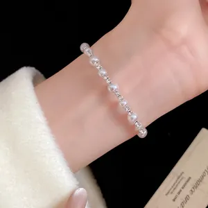 Vista detallada de una elegante pulsera de perlas y diamantes de imitación en la muñeca