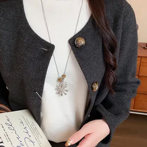 Close-up of elegant tiger eye beaded necklace with silver flower pendant on a model.