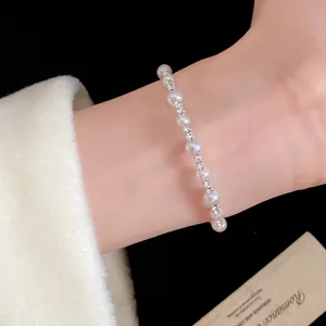 Primer plano de una pulsera de perlas vintage francesa con diamantes de imitación en la muñeca