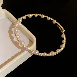 Primer plano de un elegante brazalete con perlas blancas y cristales brillantes.