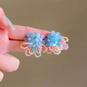 Dettaglio di orecchini floreali a perno in stile dopamina con perle blu e fiori