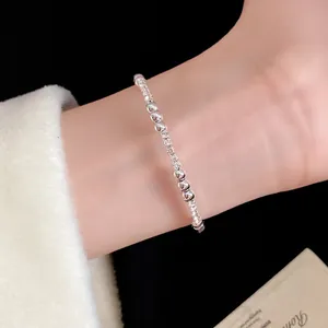 Primer plano de una pulsera de cuentas plateadas en la muñeca, estilo vintage francés