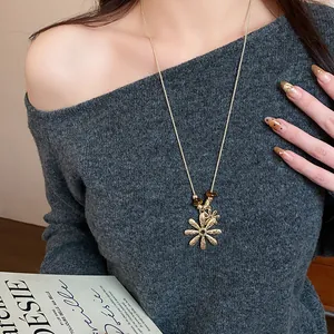 Close-up detail of a elegant gold flower pendant necklace with tiger eye beads on a model