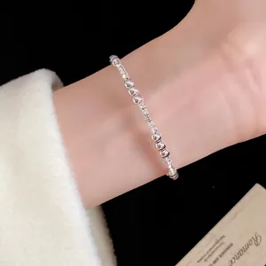 Vista detallada de una pulsera de cuentas plateadas brillantes en la muñeca