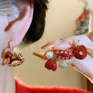 Detailed macro shot of red enamel earrings with rocking horse and cherry designs