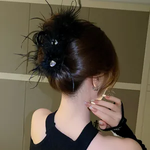 Elegant black feather hair claw clip with rhinestones worn by a model in a bun.