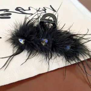 Detail view of a black feather hair claw clip with heart-shaped rhinestones