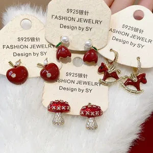 Detailed view of red enamel stud earrings featuring apple, pony, and mushroom motifs