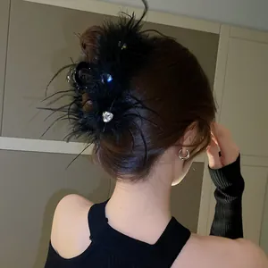 Close-up of elegant black feather hair claw clip with sparkling rhinestones worn by a woman.