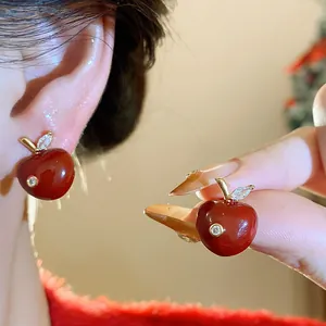 Close-up of elegant red enamel apple earrings with sparkling zircon accents.
