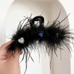 Detailed view of a black feather hair claw clip featuring sparkly heart-shaped rhinestones