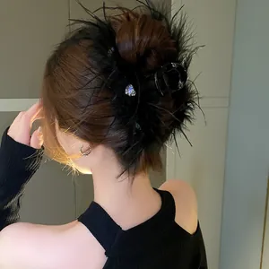 Detail view of an elegant black feather hair claw clip with rhinestones worn on an updo.