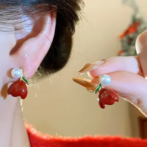 Detail of red enamel tulip stud earrings with white pearl and green leaf accent.