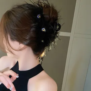Detailed view of a black feather hair claw clip with rhinestones worn by a model