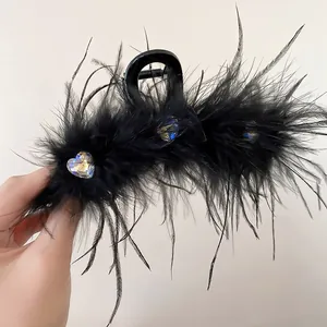 Detail view of black feather hair claw clip with heart-shaped iridescent rhinestones