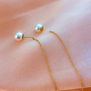 Elegant gold chain threader earrings featuring white pearls on silk background