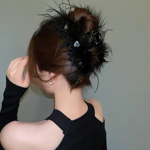 Close-up of elegant black feather hair claw clip with sparkling heart rhinestones