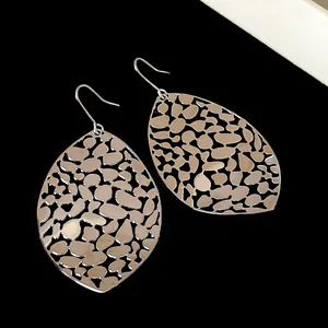 Macro detail of hollow metal leaf earrings with geometric cutout patterns