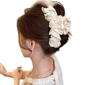Élégante pince à cheveux française en tissu à volants crème vue sur cheveux foncés